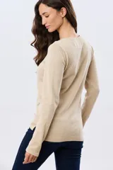 Buzo tejido de algodón color beige, de manga larga, con cuello redondo y delicados motivos bordados distribuidos en la prenda.