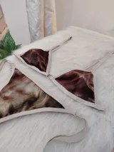Conjunto de bikini confeccionado en terciopelo con estampado en tonos marrones degradados. El corpiño es de estilo triangular con breteles regulables y cierre frontal con argolla metálica. La bombacha es de corte brasilero, con tiras laterales ajustables para atar.