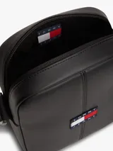 Bandolera reporter de poliuretano negro, con cierre de cremallera, correa ajustable y parche con el logo de Tommy Jeans en la parte delantera.