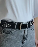 Cinturón de cuero marrón oscuro con tachas metálicas redondas en tonos bronce, plata y dorado. Hebilla rectangular de metal con acabado envejecido.