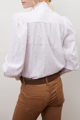 Camisa blanca de manga corta con cuello mao y volados, botones frontales y bordados de hojas y flores en color dorado.