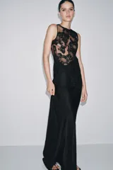 Vestido largo de corte recto con cuello redondo y diseño sin mangas. Presenta un cuerpo superior confeccionado en tejido mesh con aplicaciones de encaje floral a tono y una falda fluida de viscosa. Incluye cierre posterior con botones forrados.