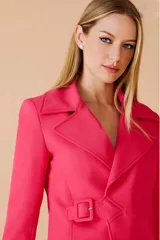 Blazer fucsia con cuello solapa, corte entallado, cierre cruzado con hebilla y mangas largas con hebilla decorativa en los puños.