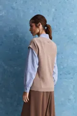 Chaleco de tejido de punto color beige claro, con cuello redondo y diseño de líneas limpias con hombros caídos y terminaciones acanaladas.