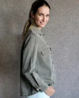 Sobrecamisa de denim azul con cuello camisero, cierre frontal con botones, mangas largas con puños abotonados y dos bolsillos con solapa en el pecho.