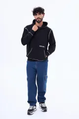 Buzo tipo canguro de felpa color negro, con capucha y bolsillo frontal. Presenta costuras a la vista en color blanco y una estampa gráfica en la espalda con la palabra 'GLOBAL' dentro de un óvalo y la frase 'STYLE IS FOR EVERYONE'.