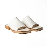 Zueco artesanal de cuero color dorado, con suela plana y taco bajo de madera con plataforma.