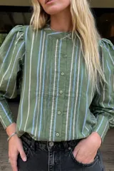 Camisa verde militar a rayas con cuello mao, botonadura frontal oculta y mangas largas abullonadas con fruncidos en los hombros.