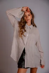 Camisa blanca de manga larga con detalle de bordados verticales en el frente y puños acampanados.