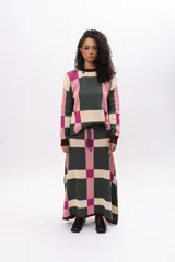 Buzo de tejido de punto con diseño geométrico de cuadros en tonos verde oscuro, rosa y crema. Presenta cuello redondo, puños y ruedo en color bordó, con mangas largas y corte holgado.