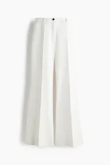 Pantalón sastrero de color blanco, tiro alto, con cierre frontal de botón y piernas acampanadas con pliegues marcados.