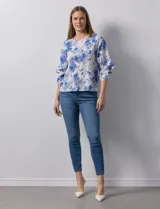 Blusa de gasa estampada con flores azules y violetas sobre fondo blanco, de manga 3/4 con volados.