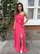 Vestido largo de fiesta color fucsia, con un solo hombro y doble volado amplio. Presenta tajo lateral y corte al bies.