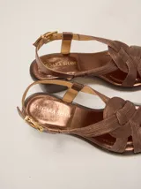 Sandalias de cuero metalizado color bronce, de taco bajo, punta cuadrada y tiras cruzadas en el empeine con textura acanalada. Posee tira al tobillo ajustable con hebilla metálica dorada.