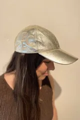 Gorra tipo baseball confeccionada en cuero ovino italiano color dorado metalizado, con bordado del monograma PEC en el lateral.