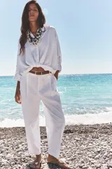 Pantalón verde oliva de lino con tiro alto, pinzas delanteras, bolsillos frontales y falsos bolsillos con solapa en la espalda. Incluye cinturón marrón y cierre delantero con cremallera, botón interior y gancho.