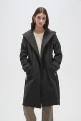 Tapado de paño color gris oscuro con solapas anchas, cierre frontal cruzado con botones y cinturón ajustable a la cintura. Posee mangas largas y bolsillos laterales.