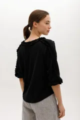 Blusa blanca de algodón suave, con mangas 3/4 y escote redondo con volados en el frente, mangas y escote.