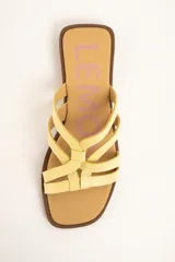 Sandalias planas de cuero color amarillo, con múltiples tiras finas entrelazadas en el empeine, suela baja y plantilla marrón.