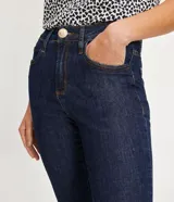 Pantalón skinny jeans azul oscuro con trabillas en la cintura, bolsillos y detalle de pespuntes contrastantes. La pieza también tiene dos botones dorados a cada lado de la barra.