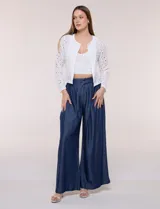 Chaqueta corta de calce recto en tejido broderie blanco, con diseño calado de perforaciones geométricas y florales, escote redondo, frente abierto y mangas largas.