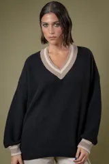 Buzo de punto en color azul marino con escote en V, puños y cuello con detalles en franjas de color turquesa y rojo. Presenta un diseño holgado de manga larga.