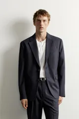 Blazer de corte relaxed fit confeccionado en tejido con lana, con solapas de muesca, manga larga con botones en los puños, bolsillos con solapa en la cadera, un bolsillo de vivo en el pecho y cierre frontal con dos botones.