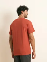 Remera básica de algodón color beige, de manga corta, con cuello redondo y un pequeño detalle bordado en el pecho.