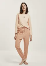 Pijama compuesto por una remera de manga larga color rosado con estampa frontal pequeña y un pantalón largo de textura acanalada en tono rosado con cintura elástica y lazo de ajuste.