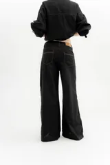 Pantalón ancho color ocre, de tiro medio, confeccionado en lino y algodón. Presenta bolsillos delanteros y traseros con triple pespunte en contratono y remaches.