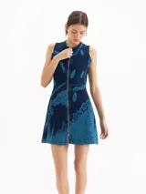 Vestido corto de denim azul con estampa cyanotype de efecto deslavado, sin mangas, escote redondo y cierre frontal completo de metal. Cuenta con corte en la cintura y silueta evasé.