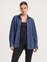 Camisa de denim azul con diseño oversize, cuello camisero, manga larga y cierre frontal de botones.