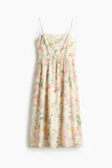 Vestido midi de color crudo con estampado floreado en tonos pastel, escote cuadrado y tirantes finos. Presenta un diseño ajustado en el torso con corte en la cintura y falda fluida con vuelo.