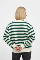 Buzo de cuello redondo a rayas horizontales en tonos beige, verde oscuro y verde claro, con un pequeño bordado de corazón rojo en el pecho.