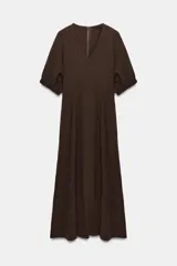 Vestido midi de color marrón chocolate, con escote en pico y mangas cortas abullonadas con puños elásticos. Presenta costuras verticales decorativas en el frente y cierre de cremallera oculta en la espalda.