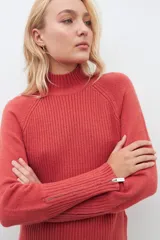 Polera de punto color ladrillo, de cuello alto y mangas largas con cierre en los puños.