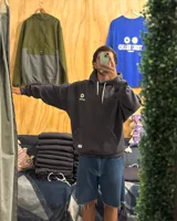 Canguro oversized color negro con estampado frontal en blanco que incluye dos soles y el texto "TRIBU BRAND".