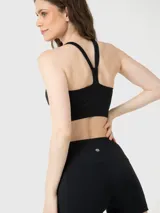 Top deportivo negro de sujeción media con espalda cruzada, confeccionado con tecnología Aloe Vera para una textura suave y elástica.