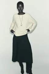 Jersey oversize de punto color crema, con cuello redondo y manga larga. Presenta costuras marcadas en los hombros y los laterales.