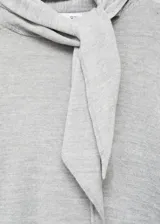 Jersey de punto fino color gris claro, de corte recto y manga larga, con cuello alto y detalle de lazada en el cuello.