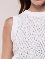 Chaleco tejido de punto calado melange, marca Elie Tahari, de color blanco. Presenta silueta semi entallada, escote a la base ligeramente elevado con terminación en punto acanalado, y sisas marcadas y ribeteadas en canalé. Confeccionado en tejido de punto con trama labrada y calados geométricos en forma de rombos, con espalda de tejido continuo y ruedo recto de largo a la cadera alta terminado en pretina ancha acanalada.