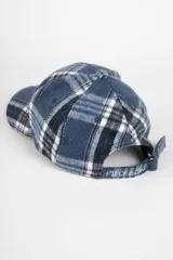 Gorro tipo baseball de tela escocesa afelpada en tonos marrón, blanco y gris.