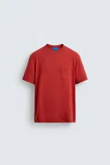 Camiseta de corte regular, color rojo ladrillo, con cuello redondo, manga corta y bolsillo tipo plastrón en el pecho.