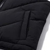 Chaleco puffer negro con cuello alto, cierre frontal completo y bolsillos laterales. Presenta un diseño acolchado con costuras en V y cordón ajustable en el ruedo.