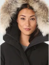 Campera negra de Canada Goose, modelo Rossclair Parka, con capucha con borde de piel, cierre frontal con botones y bolsillos laterales.