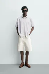 Camisa azul marino de corte regular fit confeccionada en tejido fluido de algodón y lino, con cuello solapa, manga corta, bolsillo aplicado en el pecho y cierre frontal con botones.