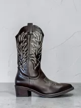 Bota estilo texana de caña media en color café, con costuras decorativas en contraste de color blanco en la caña y el empeine, y taco cuadrado.