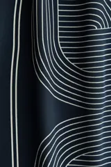 Pantalón de tiro alto color azul marino, confeccionado en tela con leve brillo, con cintura elástica y diseño de piernas rectas con estampado geométrico de líneas claras.