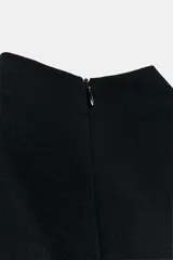 Vestido corto negro de cuello subido y sin mangas, con detalle de fajín drapeado en la cintura y caída lateral asimétrica.