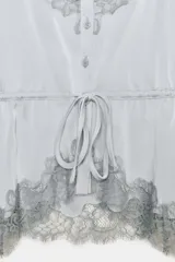 Top satinado color celeste con escote en pico y tirantes finos. Presenta detalles de encaje gris en el escote y el bajo, y una cintura ajustable con lazada.